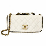 A Chanel shoulder bag in off-white quilted leather with a gold-tone interlocking CC logo, a gold and black chain strap, and a black-and-gold patterned trim, shown against a plain white background.