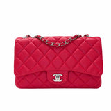 A red quilted leather shoulder bag with a diamond pattern, a front pocket, and a chain strap, shown against a plain white background.