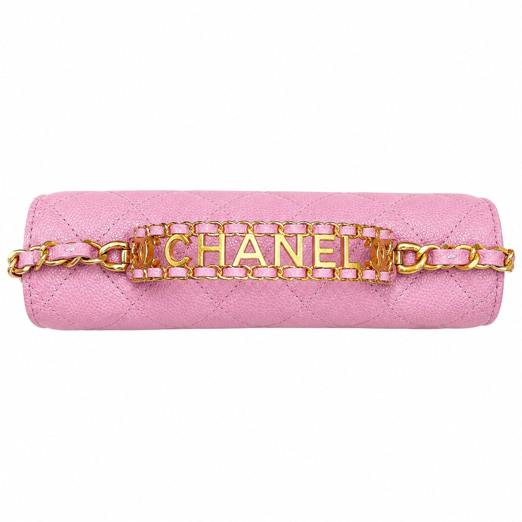 A pink quilted leather shoulder bag with a gold-tone chain strap and a central gold-tone metal bar spelling 'CHANEL' in large letters.