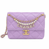 A Chanel flap shoulder bag in lavender quilted suede, featuring a gold-tone chain strap embellished with white pearls and a rhinestone-embellished CHANEL logo, with a gold interlocking CC turn-lock closure on a white background.