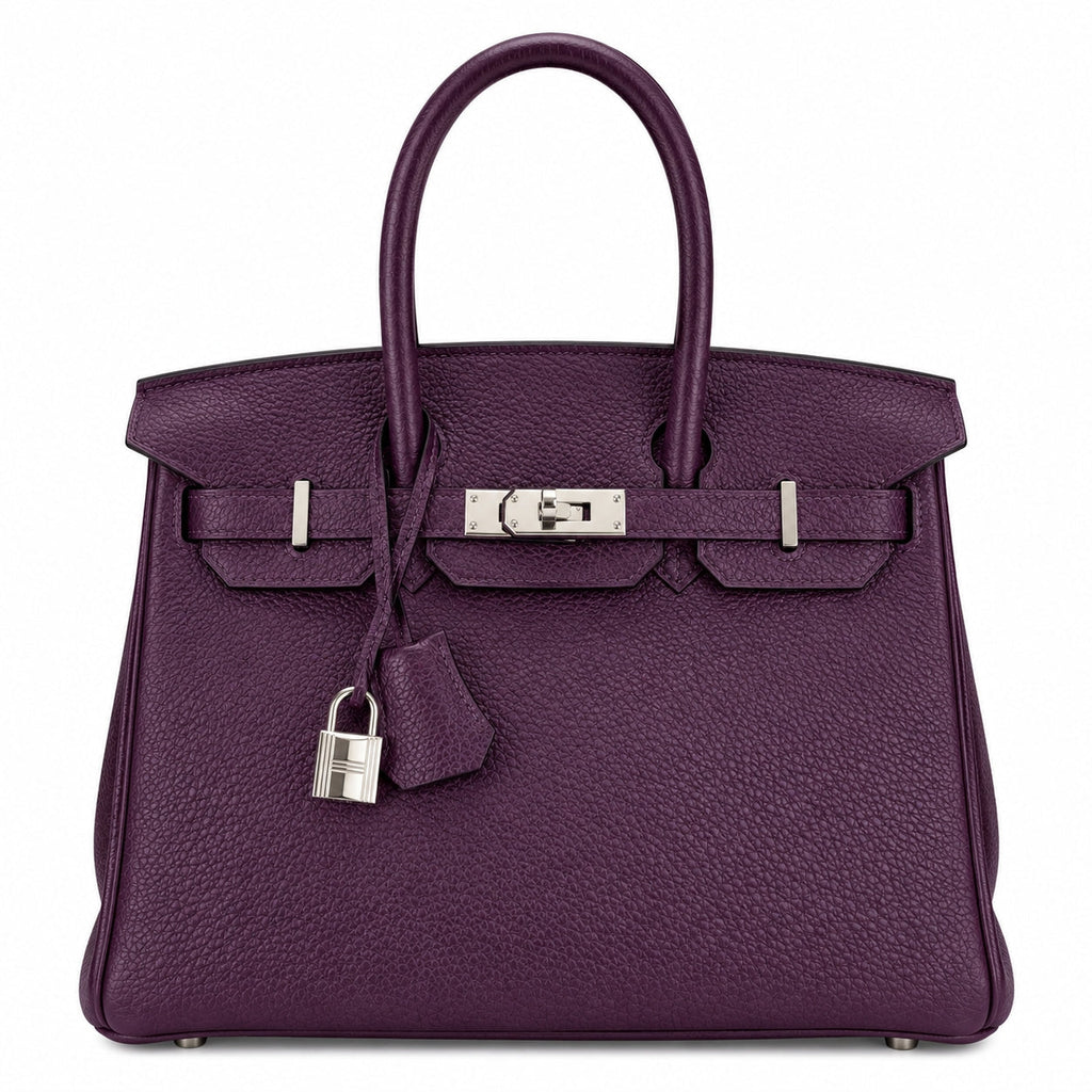 A purple pebbled leather handbag with silver-tone hardware, featuring dual top handles, a front strap closure, and a hanging padlock with clochette, photographed on a plain white background.
