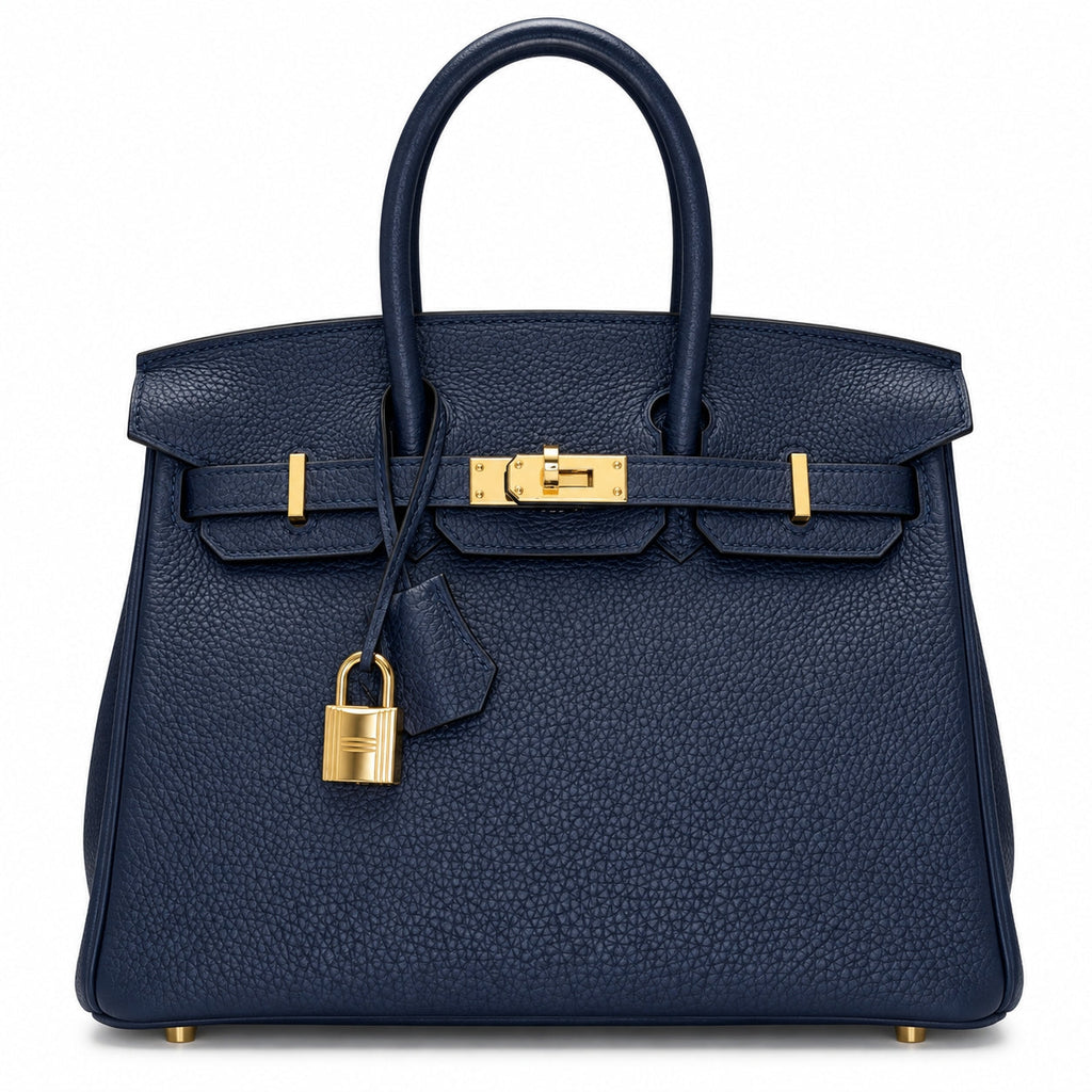 A navy blue pebbled leather handbag with gold-tone hardware, featuring dual top handles, a front strap closure, and a hanging padlock, shown against a plain white background.
