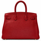 A red pebbled leather handbag with dual top handles and gold-tone hardware, photographed against a clean white background.