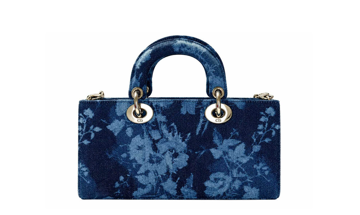 A structured navy blue handbag with a floral tie-dye pattern, featuring a top handle and gold-tone hardware.