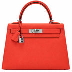 A structured top-handle handbag in bright orange-red textured leather with silver-tone hardware, shown against a plain white background.